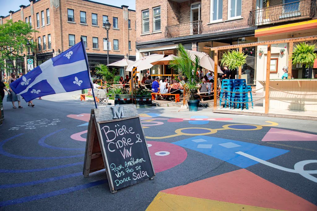 Lively Montreal street with Quebec flag and outdoor cafe setting.