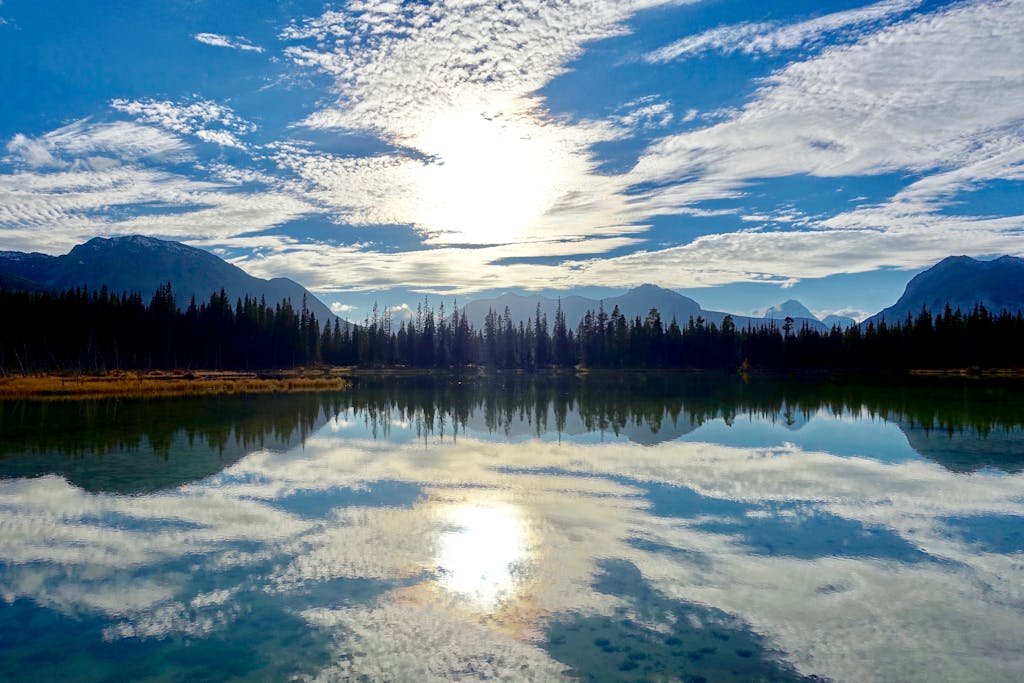 Peaceful mountain landscape with a lake reflecting the sky and clouds.